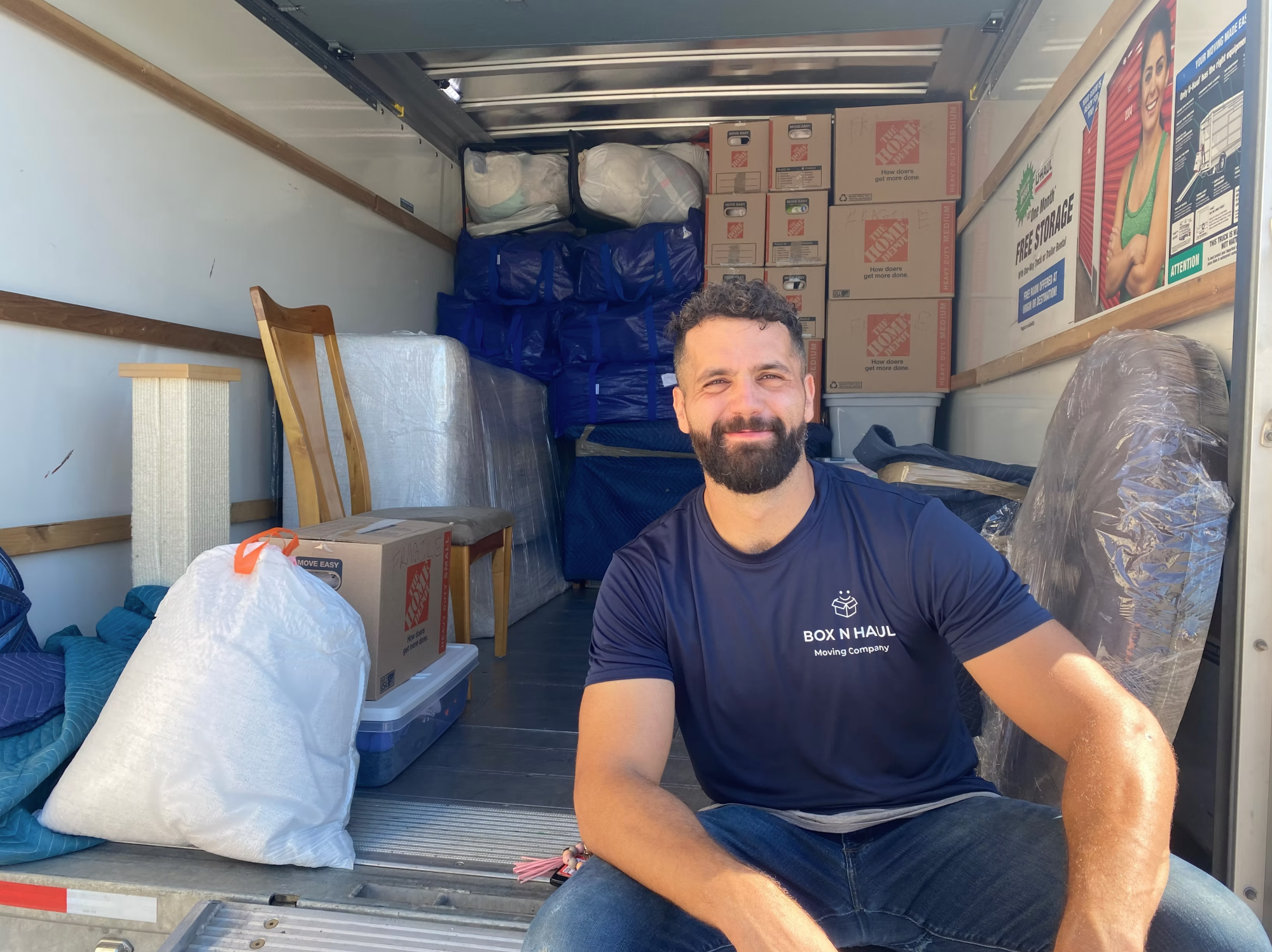 Smiling Box N Haul mover sitting in the back of a fully loaded moving truck packed with wrapped furniture and boxes.