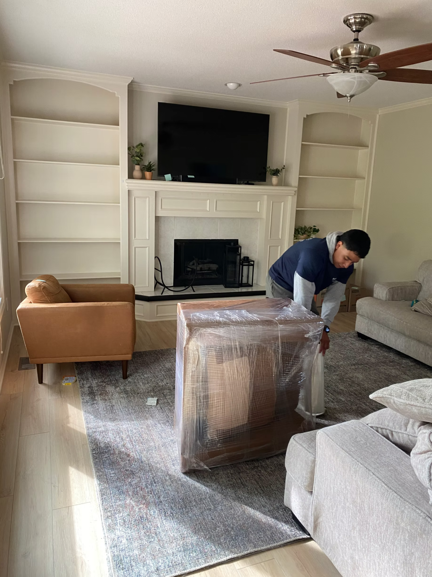 Box N Haul mover carefully shrink-wrapping furniture in a living room.